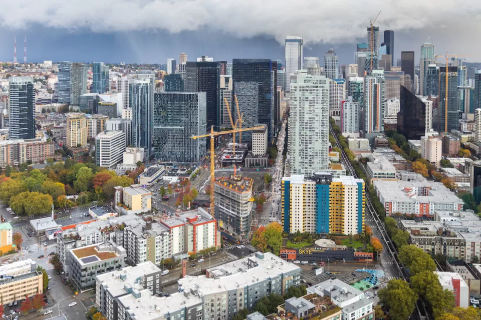 View of downtown Seattle with construction cranes and cloudy sky as seen from top of Space Needle.